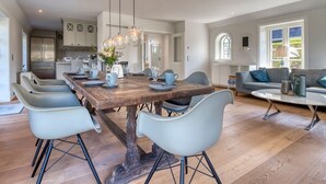 Un'ampia cucina con elettrodomestici moderni, un tavolo da pranzo in legno con sedie e un accogliente soggiorno con divano e tavolino.
