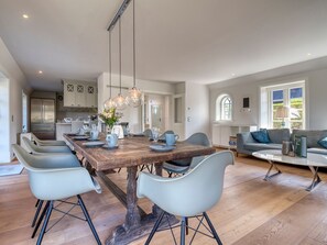 A spacious kitchen with modern appliances, a wooden dining table with chairs, and a cozy living area with a sofa and a coffee table.