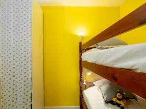 A bunk bed room with a yellow wall, a white curtain with a pattern, and a small lamp. - East Land by Interhome (La Grande Motte)