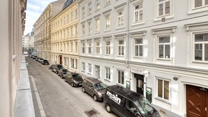 Eine Reihe geparkter Autos entlang einer Straße, mit einem Gebäude, das eine Schilder für das Vienna Schick Bar zeigt.