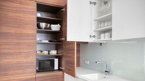 Eine moderne Küche mit Holzschränken, einer eingebauten Mikrowelle und einem weißen Spülbecken.
