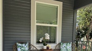 A porch with two wicker chairs, a small round table with a potted plant, and a window with white shutters. - Newly renovated home walkable to Downtown/Restaurants/Park (Ukiah)