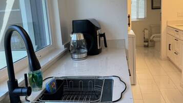 Una cocina moderna con un lavamanos de acero inoxidable, una cafetera y un escurreplatos.