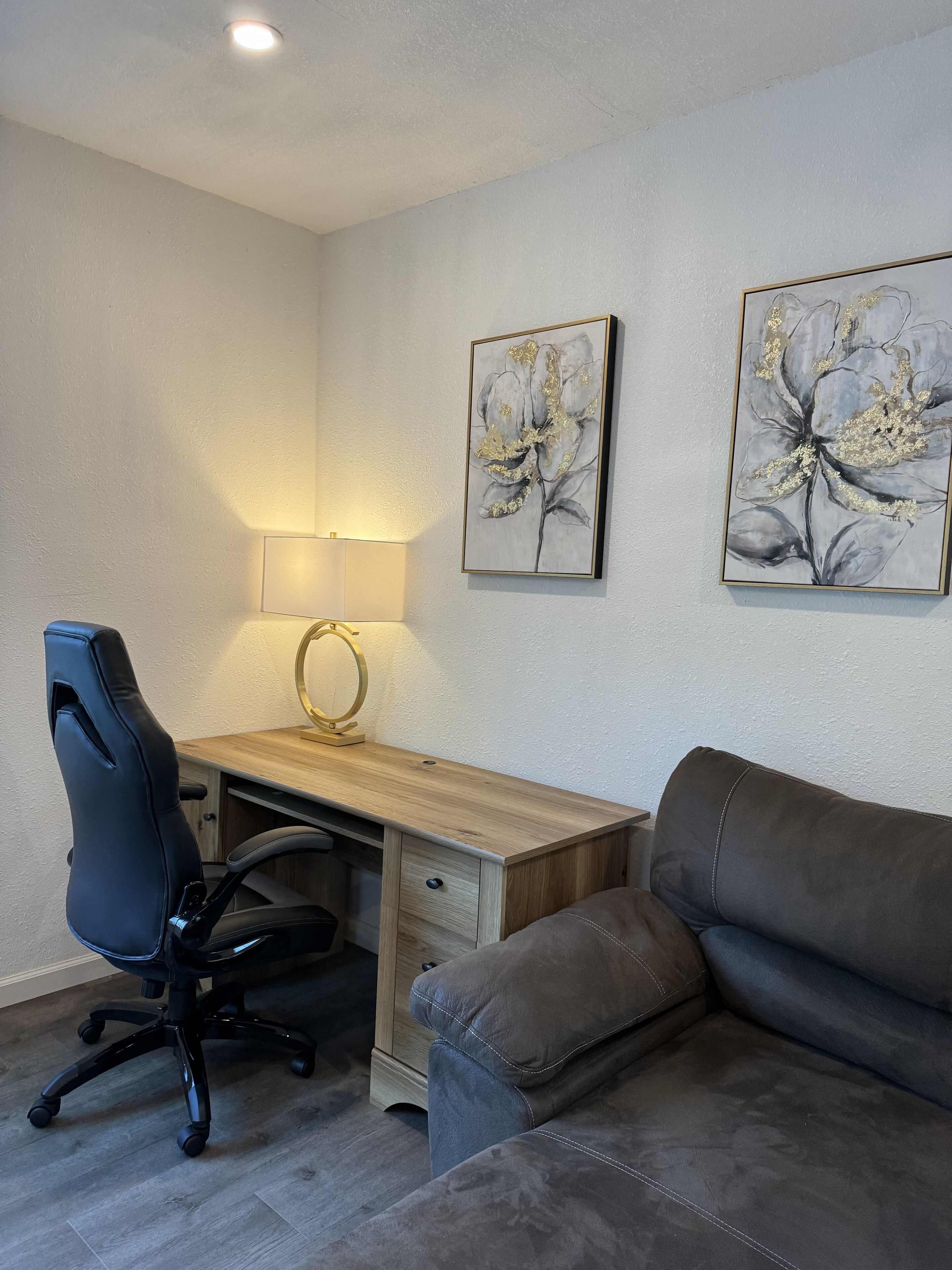 A modern office space with a desk, office chair, and a leather couch.