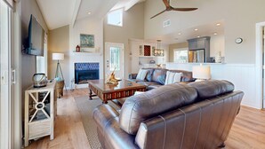 A spacious living room with a leather sofa, wooden coffee table, and a fireplace. - Shared Pool, Boardwalk to the Beach, Pet Friendly (Port Aransas)