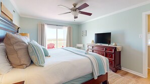 A bedroom with a bed, a dresser, a television, and a ceiling fan. - Shared Pool, Boardwalk to the Beach, Pet Friendly (Port Aransas)