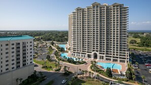 Un hotel di grandi dimensioni con diversi piani, una piscina e un'area parcheggio.