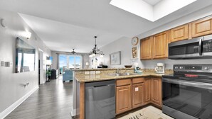 Una cucina moderna con ripiani in granito, mobili in legno, elettrodomestici in acciaio inossidabile e vista all'esterno.