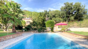 Una piscina rectangular con agua azul cristalina, rodeada por un borde de piedra y un camino de piedra.