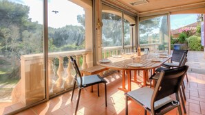 Un patio iluminado por el sol con una mesa redonda, sillas y vistas a un jardín exuberante.