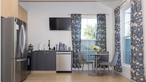 A modern kitchen with a built-in dishwasher, a stainless steel refrigerator, and a flat-screen TV mounted above the counter. - Hollywood Family Nest in Burbank, Steps to Studios! (Burbank)