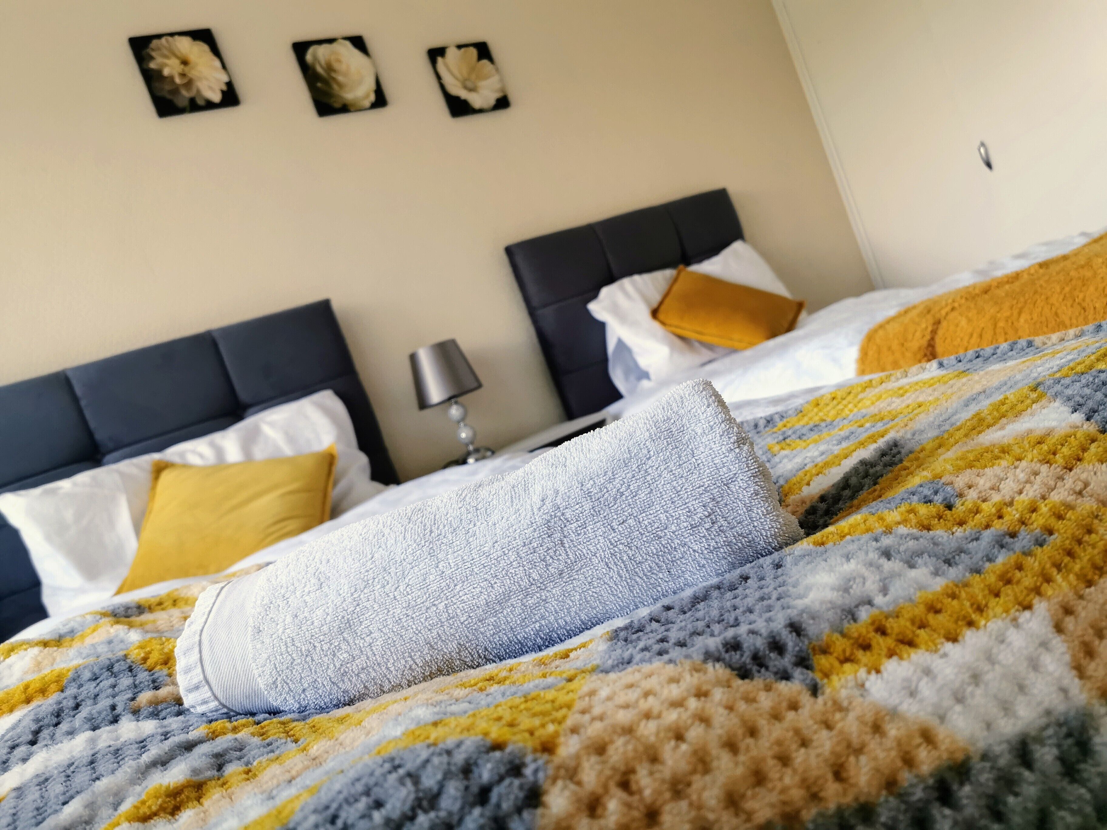 Un lit avec une couverture à rayures, une lampe et deux oreillers posés sur la tête de lit.