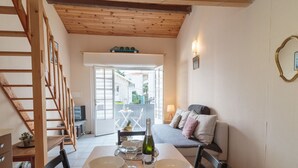 Una zona de menjador amb taula ben posada per a dues persones, un sofà i una escala.
