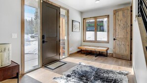 A modern entryway with a sliding glass door, a bench, and a rustic wooden door.