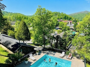 A swimming pool with lounge chairs, surrounded by greenery and a view of a hillside. - Rustic Cottage Style 10 min walking to Downtown Gatlinburg (Gatlinburg)