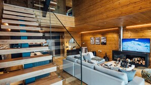 Un intérieur moderne avec un escalier en bois, un espace de vie comprenant un canapé, une cheminée et un téléviseur.