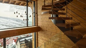 Un intérieur moderne avec un escalier en colimaçon, de grandes fenêtres et une vue sur un paysage enneigé.