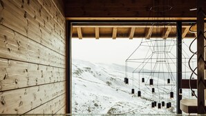 Une pièce aux murs en bois et dotée d’une grande fenêtre donnant sur un paysage enneigé.
