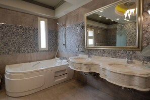 A bathroom with a large bathtub, two sinks, and a large mirror.