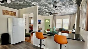 Una cocina moderna con una isla central, taburetes de bar y un techo con un diseño original.