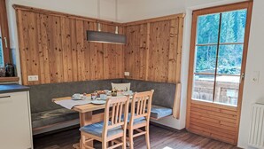 Et hyggeligt spiseområde med et træbord, to stole og en bænk.