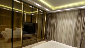 A modern bedroom with a large bed, a glass partition, and a sliding door leading to a bathroom. - Villa in palm hills-the crown (6th of October City)