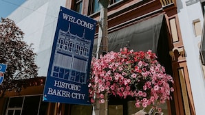 A historic Baker City hotel with a welcome sign, a street lamp, and a hanging flower basket.