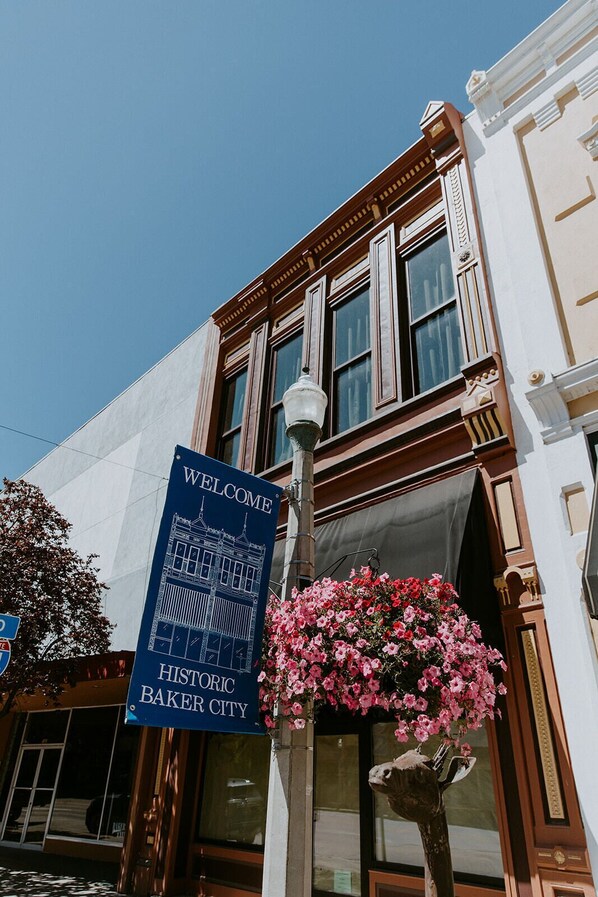 A historic Baker City hotel with a welcome sign, a street lamp, and a hanging flower basket.