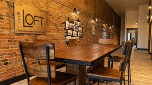 A long wooden table with metal chairs in a room with exposed brick walls and a sign that reads "The Loft".