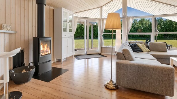 A cozy room with a wood-burning stove, a sofa, and a lamp.