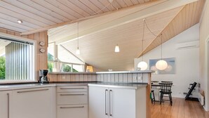A modern kitchen with wooden flooring, a built-in island, and pendant lighting.