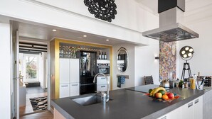 Una cocina moderna con una isla grande, electrodomésticos de acero inoxidable y un elemento decorativo en la pared.