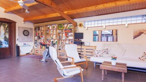 A spacious living area with a wooden ceiling, a white sofa, two white chairs, a wooden coffee table, and a bookshelf filled with various items. - Authentic House With Playroom and Infrared Sauna (Bilzen)