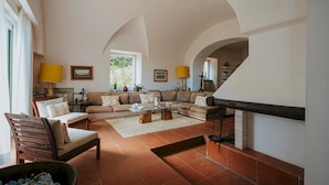 A spacious living room with a fireplace, a sofa set, and a dining table. - Villa White by Elite Villas (Capri)