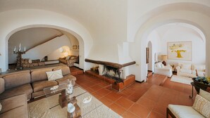 A spacious living room with a fireplace, sofas, and a large painting on the wall. - Villa White by Elite Villas (Capri)