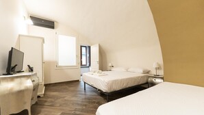 Quarto com cama, escrivaninha e televisão.