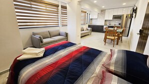 A modern bedroom with a large bed, two sofas, a dining area, and a kitchen. - Centro Expositor, Feria, Estadios, Acuario, Planetario (Heroica Puebla de Zaragoza)