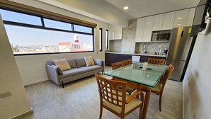 A modern kitchen with a dining area, large windows, and a city view. - Centro Expositor, Feria, Estadios, Acuario, Planetario (Heroica Puebla de Zaragoza)