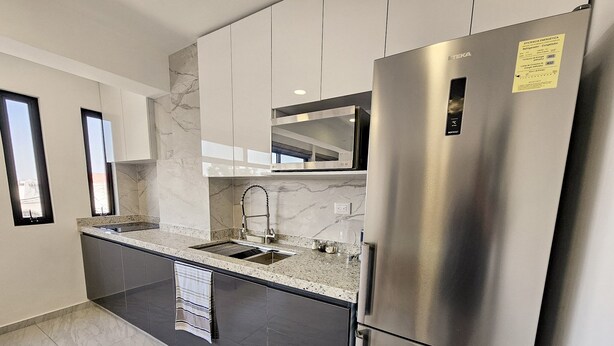 A modern kitchen with a stainless steel refrigerator, a built-in microwave, and a sink with a faucet. - Centro Expositor, Feria, Estadios, Acuario, Planetario (Heroica Puebla de Zaragoza)