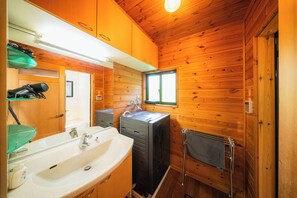 A cabin-style bathroom with a sink, mirror, and wooden walls. - Wakuraba (Hakuba)