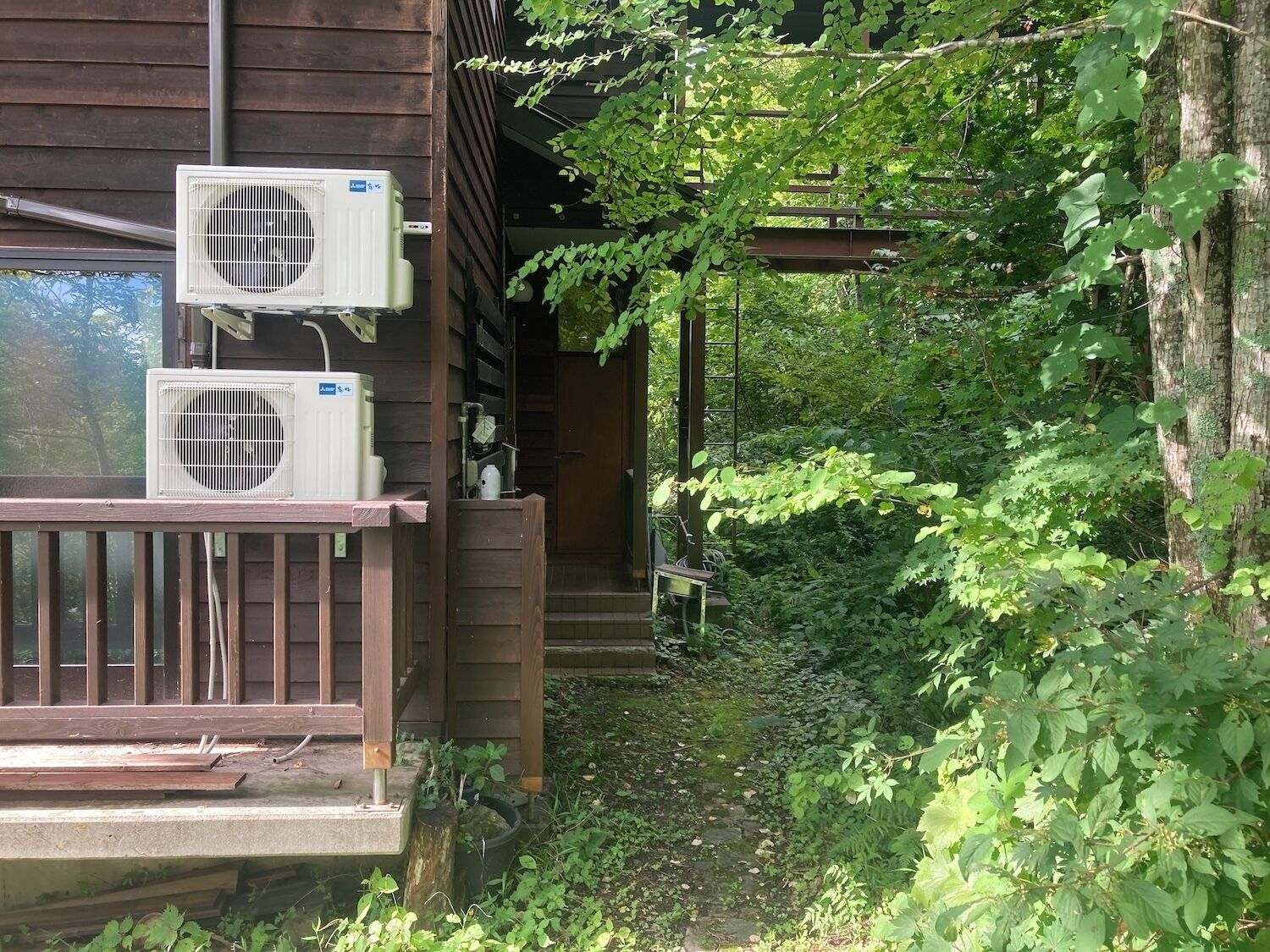 A wooden cabin with two air conditioning units mounted on the exterior wall.