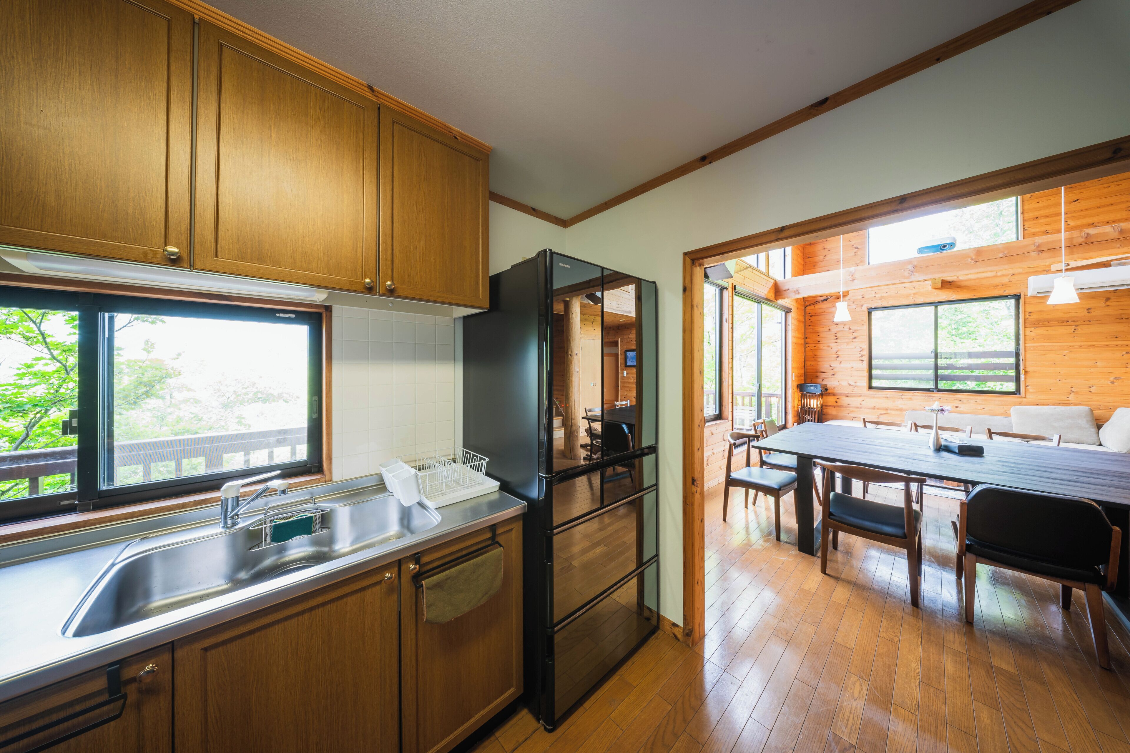 A modern kitchen with wooden cabinets, a stainless steel sink, and a black refrigerator.