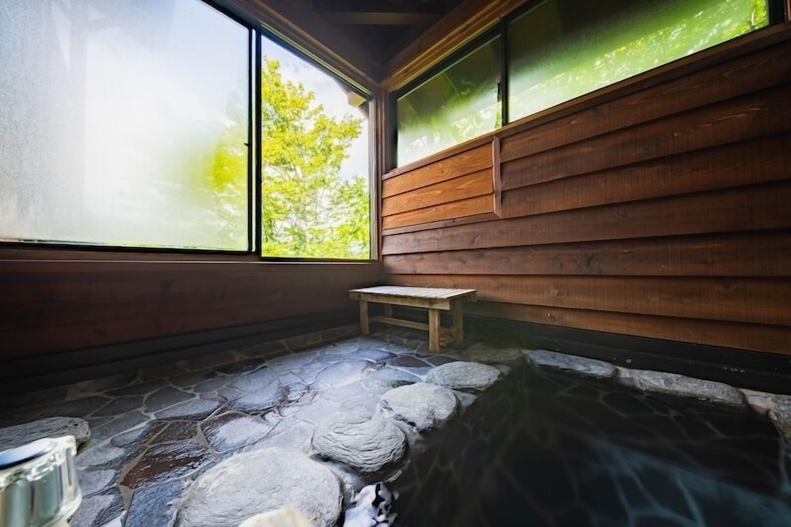 A stone hot spring area with wooden walls and a bench.