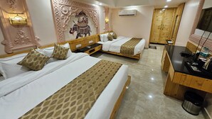 A hotel room with two beds, a wooden desk, a ceiling fan, and a decorative wall. - The Mewar Palace and Resort (Shivpuri)