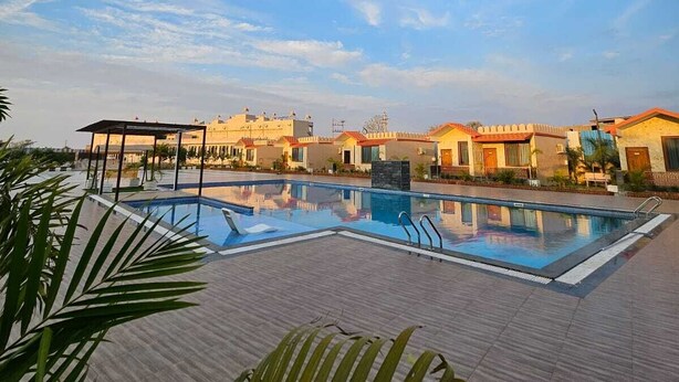A swimming pool with a clear blue sky and a few clouds in the background. - The Mewar Palace and Resort (Shivpuri)