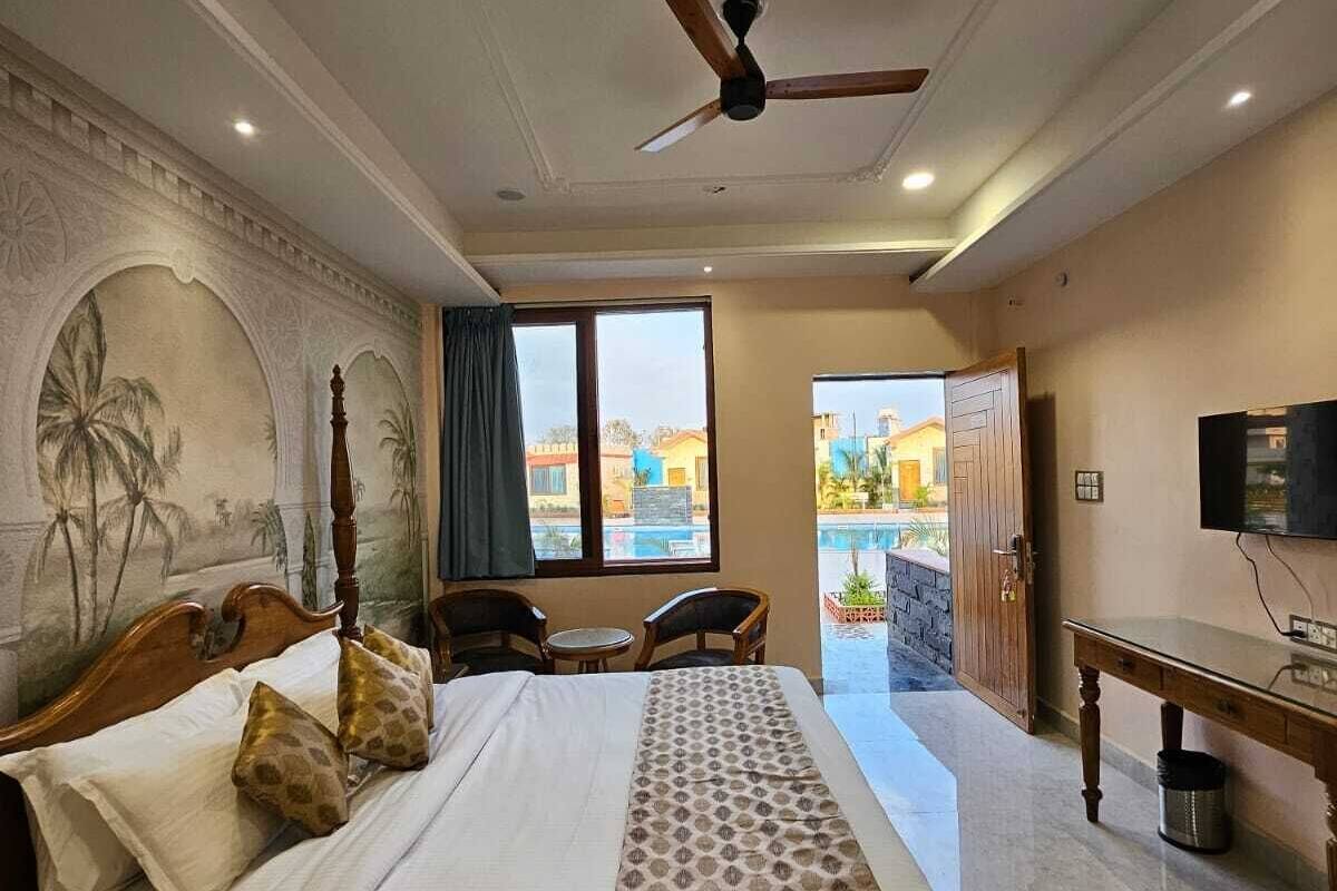 Une chambre d’hôtel avec un grand lit, un ventilateur de plafond, une télévision et une vue sur l’extérieur.