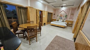 A room with a wooden bed, a dining table with chairs, and a large window with curtains. - The Mewar Palace and Resort (Shivpuri)