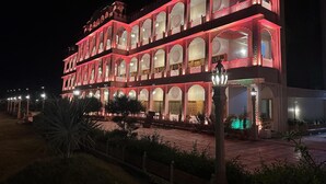 A multi-story building with ornate arches and balconies, illuminated by warm lighting. - The Mewar Palace and Resort (Shivpuri)