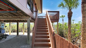 Un escalier en bois mène à un balcon d’où l’on peut admirer des palmiers et la végétation du désert.