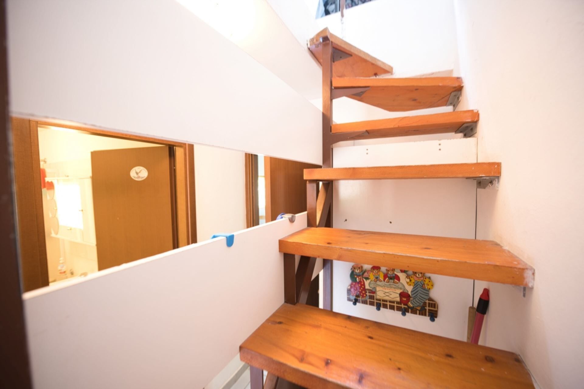 Een smalle trap met houten treden en een klein tafeltje onderaan.